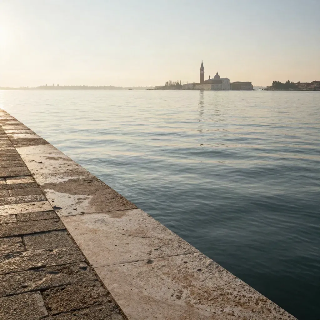 Laguna di Venezia all’alba dorata con campanili lontani e acqua calma sotto la foschia.
